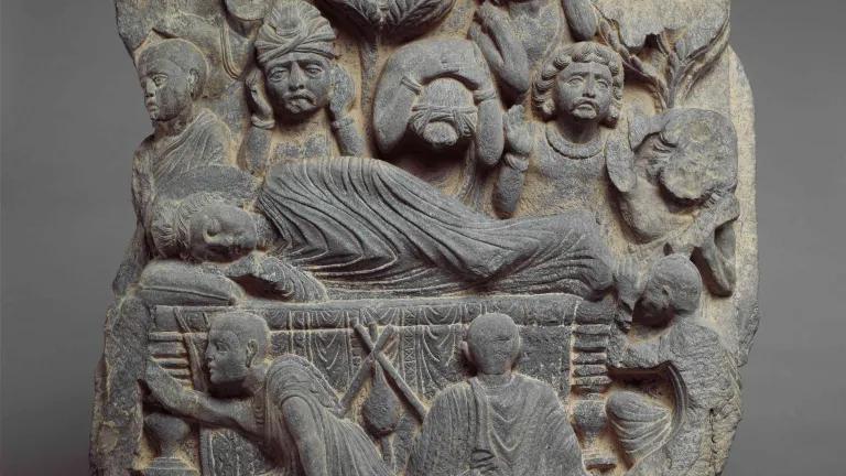Buddha lies on his deathbed with figures surrounding him, some lamenting