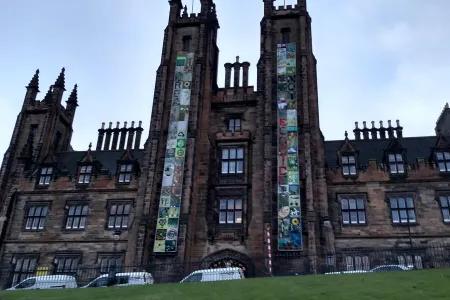 The front of New College building with two banners hanging on the towers