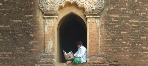 Man reading a newspaaper at Pagan