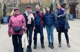 Five happy people standing in front of historic buildings